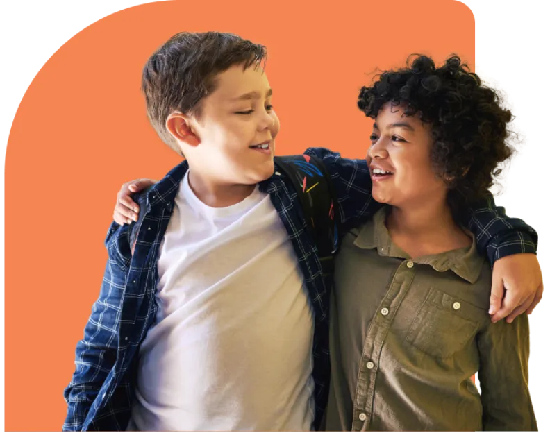 Two kids beam at each other, arms slung over shoulders in a moment of pure camaraderie. One rocks a plaid shirt over a white tee, while the other sports a green button-up. Against an orange background, it’s like capturing nostalgia straight out of a Youth Slang Dictionary snapshot.