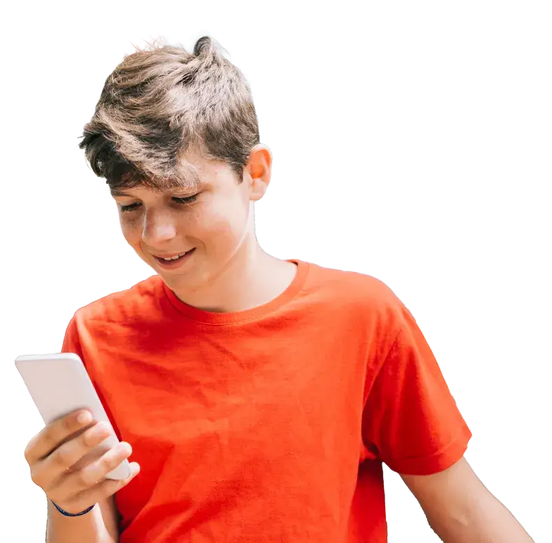 A boy in a red t-shirt is smiling while looking at a smartphone in his hand. With short brown hair, he stands against a plain background, seemingly captivated by the impact of screen time on his digital adventures.