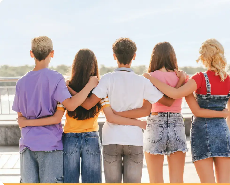Amidst a sunny, open area with trees in the distance, five friends stand closely together with their backs to the camera. Dressed in casual summer attire, they seem determined to support each other through lifes challenges, even as they discuss the profound effects of porn addiction.