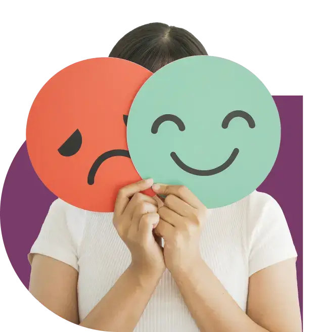 A person holds two large circular emoji masks to their face: one red with a sad expression and the other green with a happy expression, symbolizing the contrasting emotions often experienced due to the effects of porn addiction. The body is visible, wearing a white shirt against a purple background.