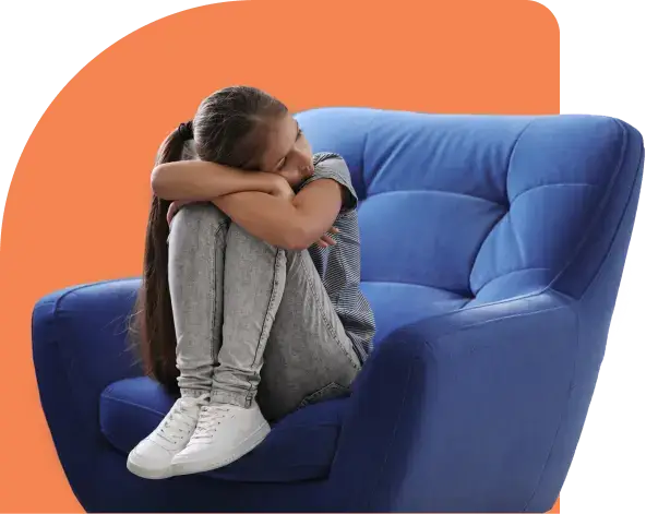 A young girl sits curled up on a blue armchair, reflecting silently with her head on her knees. Her long hair cascades over a striped shirt, jeans, and white sneakers. The solid orange background adds warmth to the scene, subtly underscoring the emotional depth and effects of introspection.
