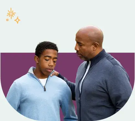 A man gently rests his hand on the shoulder of a younger person who is looking down, perhaps discussing how to deal with cyberbullying. They are both wearing casual clothing. The background features a simple two-tone design with a small sparkle icon in the corner.